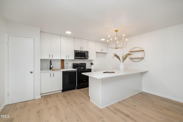 kitchen featuring white cabinets, light countertops, light wood-type flooring, black appliances, and a sink