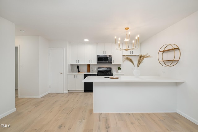 kitchen with light countertops, white cabinets, light wood-type flooring, a peninsula, and black appliances