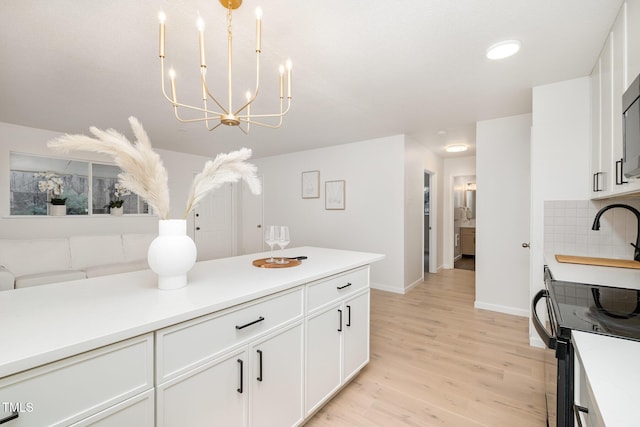 kitchen with light countertops, light wood-style flooring, backsplash, and white cabinetry