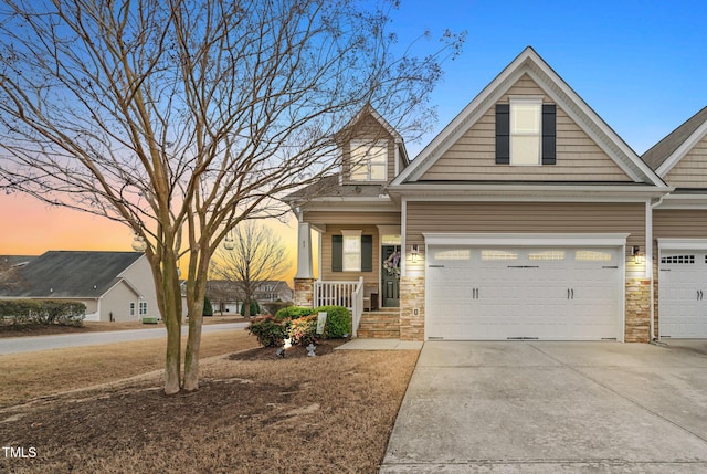 view of front facade with a porch, an attached garage, stone siding, and driveway