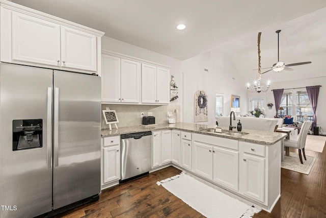 kitchen with appliances with stainless steel finishes, a sink, a peninsula, white cabinets, and dark wood-style floors