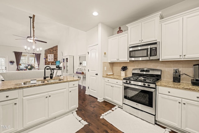 kitchen featuring stainless steel appliances, a sink, ceiling fan, vaulted ceiling, and tasteful backsplash