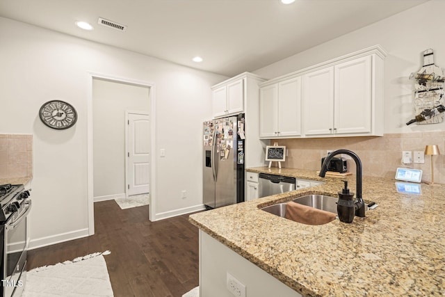 kitchen featuring stainless steel appliances, light stone countertops, a sink, white cabinetry, and recessed lighting