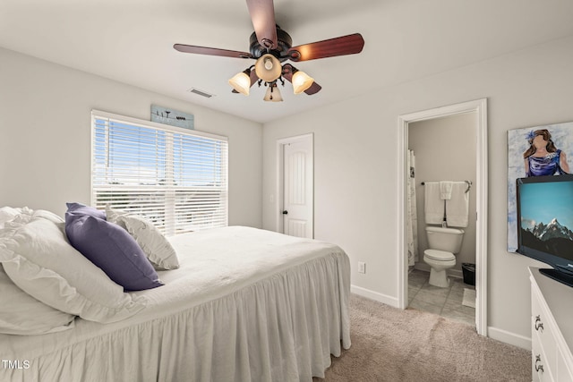 bedroom with light colored carpet, baseboards, ensuite bath, and ceiling fan