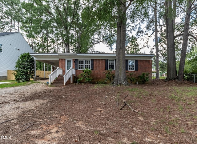 single story home featuring a carport, brick siding, driveway, and fence