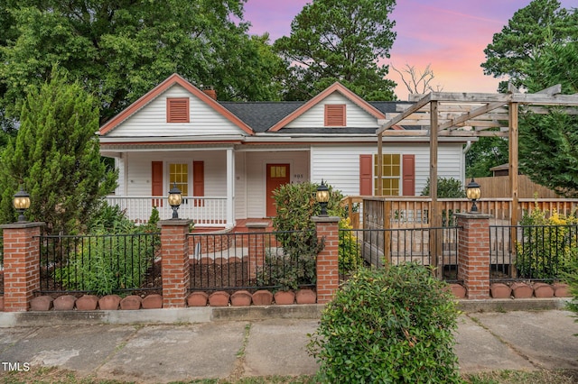 view of front of house with a fenced front yard, covered porch, a shingled roof, and a pergola