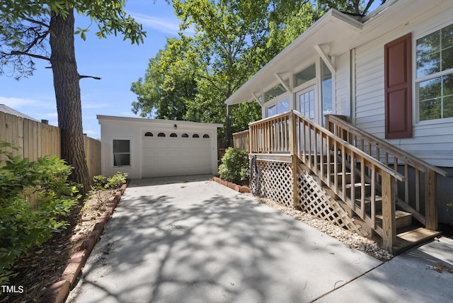 view of side of home featuring an outbuilding, concrete driveway, fence, and a garage