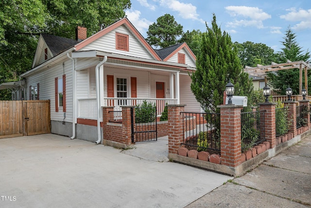 view of front of home featuring a chimney, covered porch, a gate, fence, and a pergola