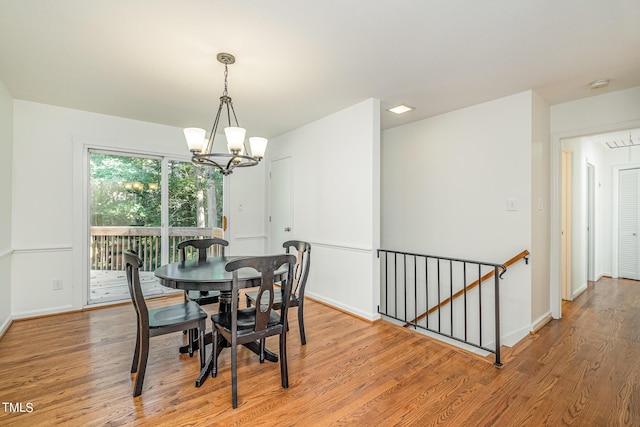 dining room featuring light wood-type flooring, a notable chandelier, and baseboards