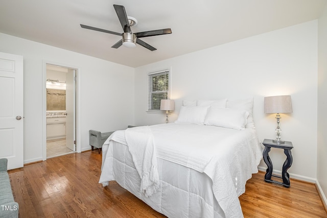 bedroom with ensuite bath, ceiling fan, baseboards, and wood finished floors