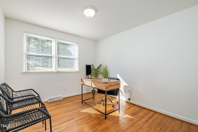 office space featuring light wood-type flooring, baseboards, and visible vents