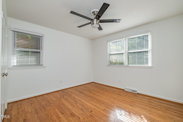 empty room featuring light wood finished floors, baseboards, visible vents, and a ceiling fan