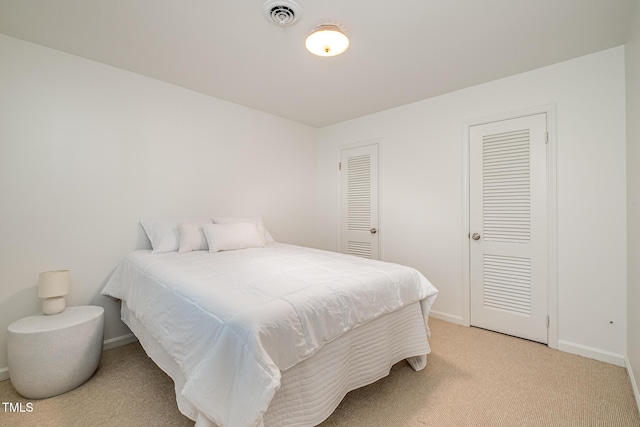 bedroom with visible vents, light carpet, and baseboards