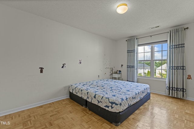 bedroom with visible vents, a textured ceiling, and baseboards