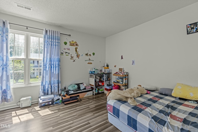 bedroom featuring a textured ceiling, visible vents, and wood finished floors