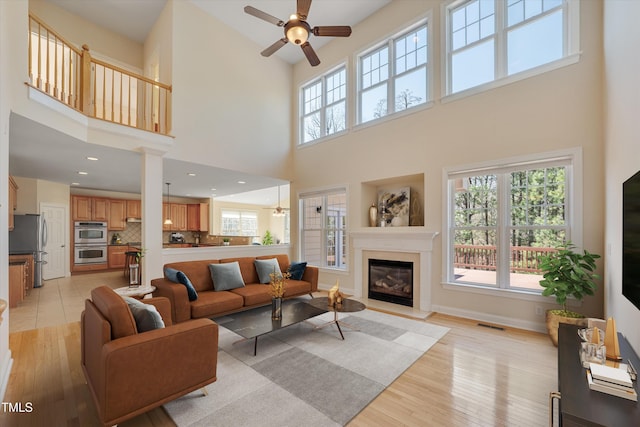 living room featuring a glass covered fireplace, plenty of natural light, and ceiling fan