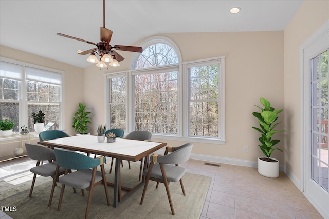 dining room with light tile patterned floors, visible vents, a healthy amount of sunlight, and vaulted ceiling