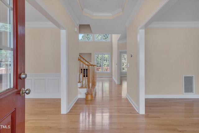 foyer with stairway, light wood-style floors, visible vents, and crown molding