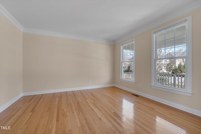 spare room featuring visible vents, light wood-style flooring, crown molding, and baseboards