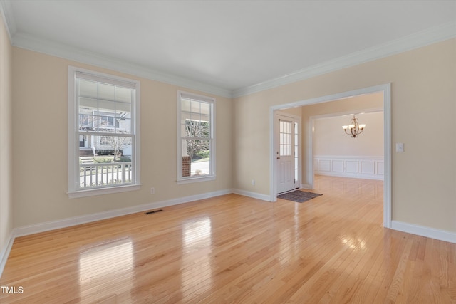 spare room with visible vents, baseboards, ornamental molding, light wood-style flooring, and an inviting chandelier