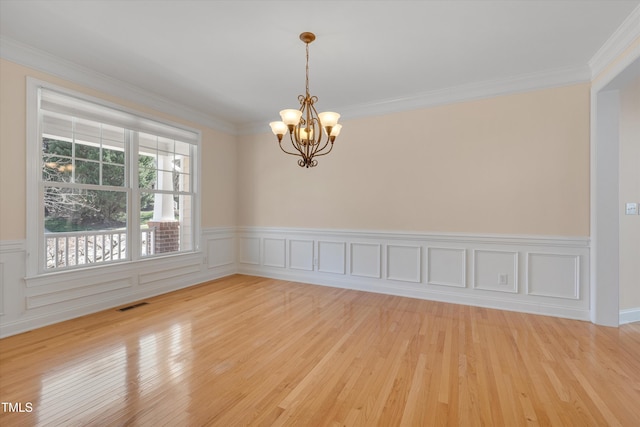 spare room with ornamental molding, visible vents, and a chandelier