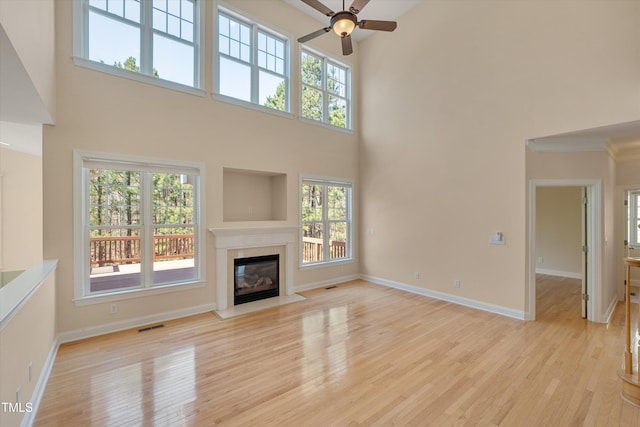 unfurnished living room featuring light wood-style flooring, a fireplace, baseboards, and ceiling fan