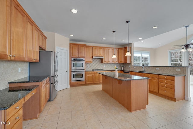 kitchen with light tile patterned floors, a peninsula, under cabinet range hood, appliances with stainless steel finishes, and a center island