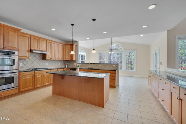 kitchen with a breakfast bar, under cabinet range hood, stainless steel double oven, a peninsula, and vaulted ceiling