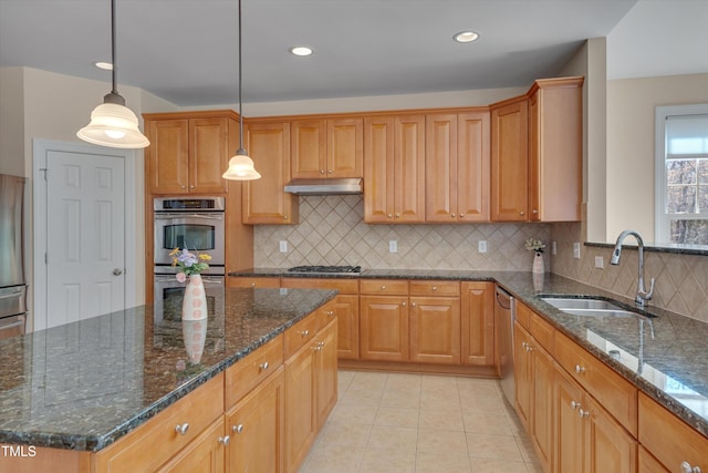 kitchen with under cabinet range hood, light tile patterned floors, appliances with stainless steel finishes, hanging light fixtures, and a sink