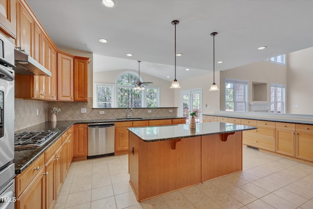 kitchen featuring a peninsula, a sink, vaulted ceiling, appliances with stainless steel finishes, and a center island