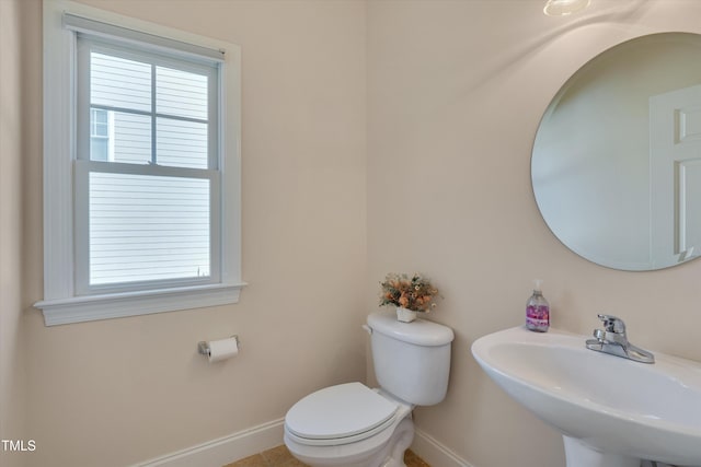 half bathroom featuring a sink, baseboards, plenty of natural light, and toilet