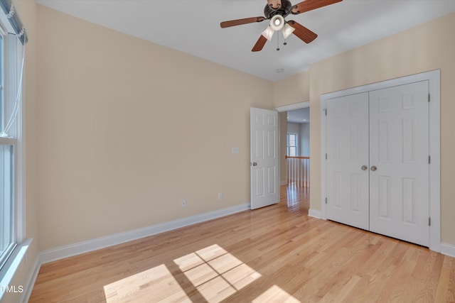 unfurnished bedroom with ceiling fan, a closet, baseboards, and light wood-style flooring