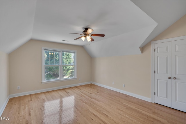 additional living space with visible vents, ceiling fan, baseboards, vaulted ceiling, and light wood-style floors