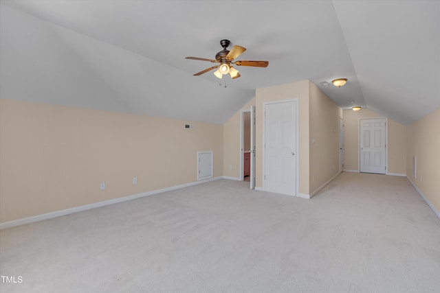 additional living space featuring a ceiling fan, baseboards, visible vents, vaulted ceiling, and light colored carpet