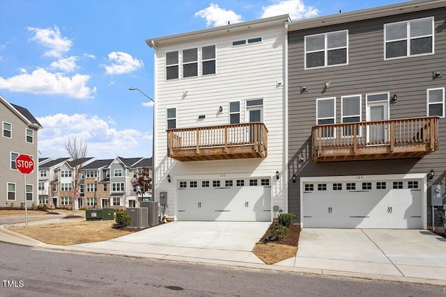 rear view of house with a residential view, cooling unit, driveway, and an attached garage