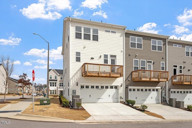 back of house featuring a garage, cooling unit, concrete driveway, and a residential view