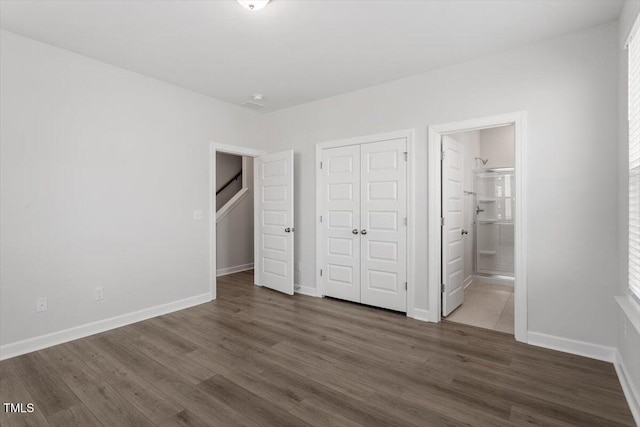 unfurnished bedroom featuring a closet, baseboards, and dark wood-type flooring