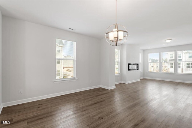 spare room featuring visible vents, dark wood finished floors, baseboards, and an inviting chandelier