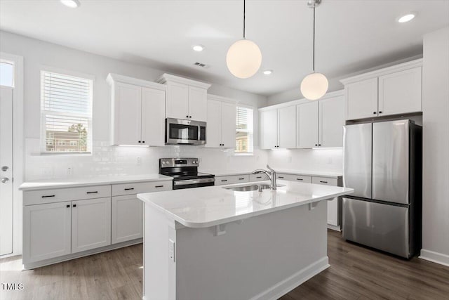 kitchen featuring appliances with stainless steel finishes, white cabinetry, a sink, and tasteful backsplash