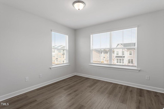 empty room featuring dark wood-style flooring and baseboards