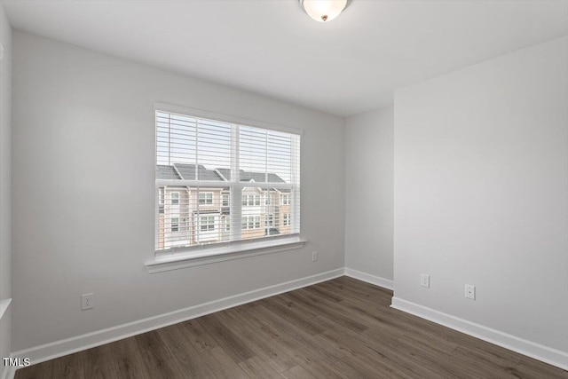 unfurnished room featuring dark wood-style floors and baseboards