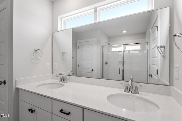 bathroom with a stall shower, a sink, and double vanity