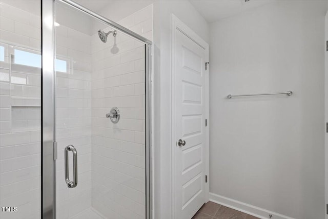 full bathroom with a shower stall and baseboards