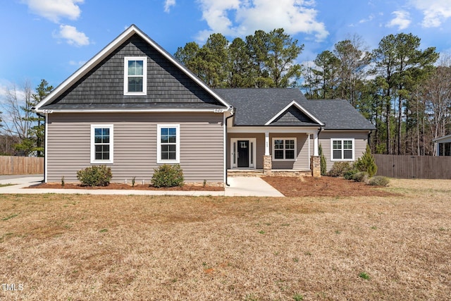 view of front of property featuring fence, a front lawn, and roof with shingles