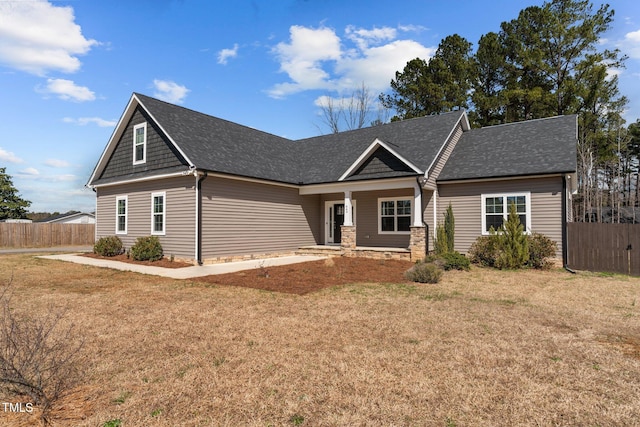 craftsman-style home featuring a front yard, stone siding, and fence