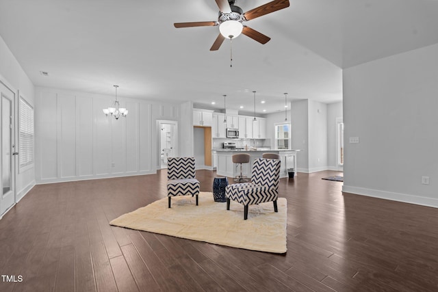 living room with ceiling fan with notable chandelier, dark wood-type flooring, recessed lighting, and baseboards