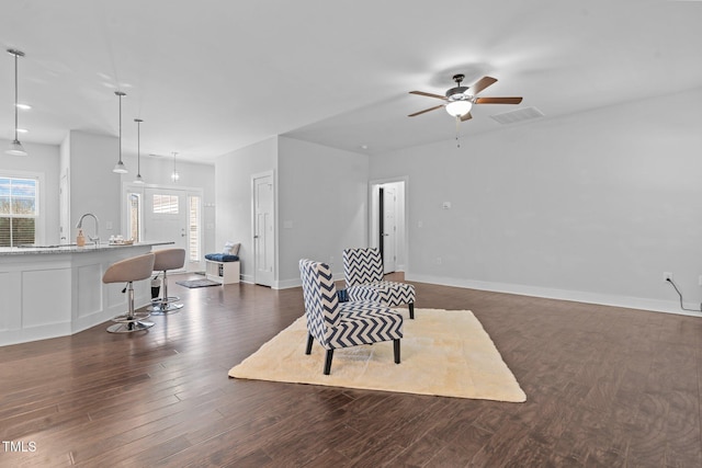 sitting room with a healthy amount of sunlight, baseboards, visible vents, and dark wood-style flooring