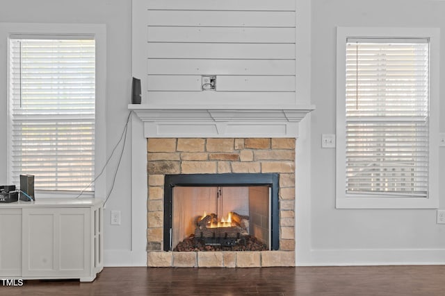 interior details with a warm lit fireplace, baseboards, and wood finished floors