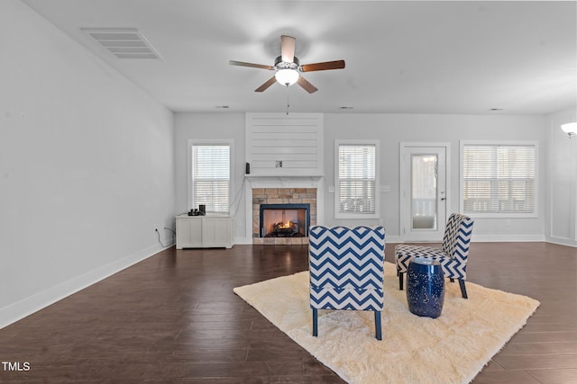 living room featuring a warm lit fireplace, plenty of natural light, visible vents, and dark wood finished floors