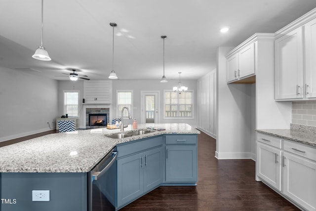 kitchen featuring dark wood-style flooring, white cabinetry, a sink, a stone fireplace, and dishwasher